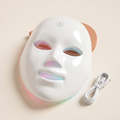 LED light face mask on a cream background